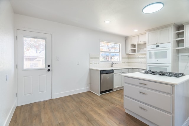 kitchen with backsplash, a healthy amount of sunlight, white cabinetry, and stainless steel appliances