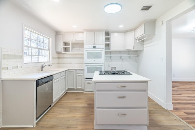 kitchen featuring white cabinetry, light hardwood / wood-style flooring, a kitchen island, and stainless steel appliances