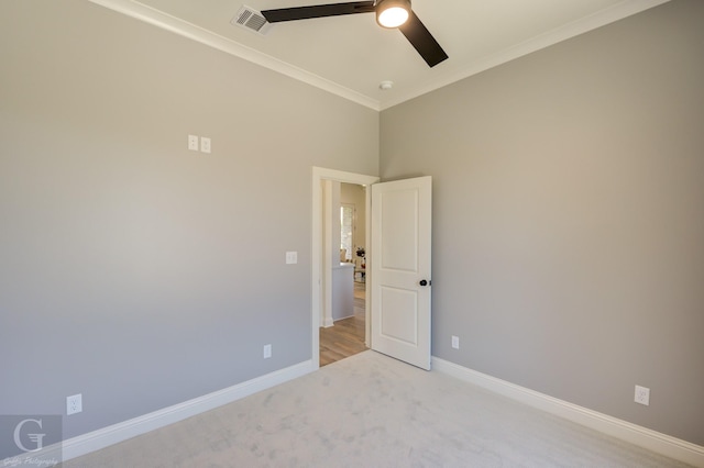 empty room featuring ceiling fan, light carpet, and ornamental molding