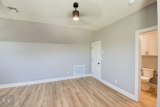 unfurnished bedroom with connected bathroom, light hardwood / wood-style flooring, vaulted ceiling, and ceiling fan