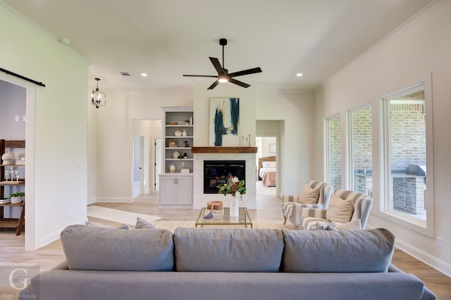 living room featuring ceiling fan, light hardwood / wood-style floors, a premium fireplace, and crown molding