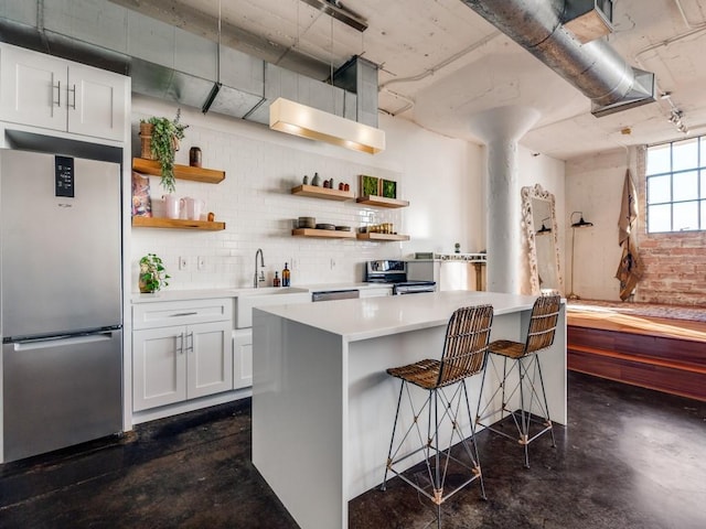 kitchen with a breakfast bar area, a center island, white cabinets, and appliances with stainless steel finishes