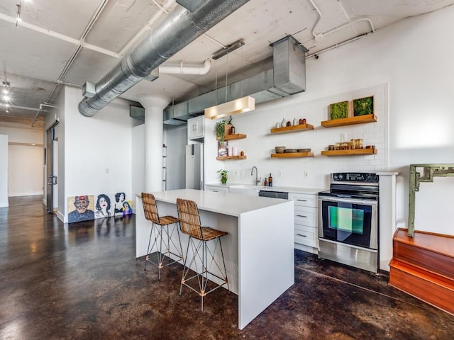 kitchen featuring appliances with stainless steel finishes, tasteful backsplash, white cabinetry, sink, and a kitchen bar