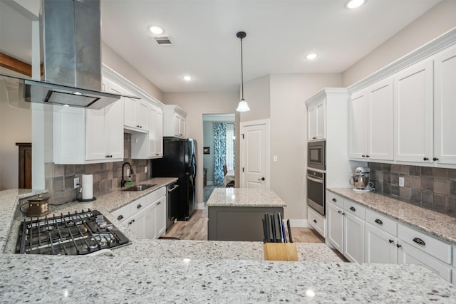 kitchen featuring island exhaust hood, backsplash, stainless steel appliances, and light stone countertops