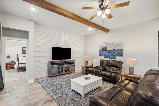 living room with beamed ceiling, light hardwood / wood-style floors, and ceiling fan