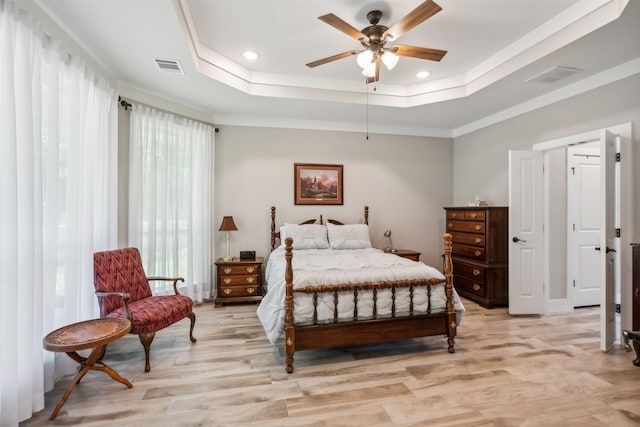 bedroom with a raised ceiling, multiple windows, and ceiling fan