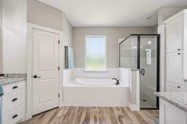 bathroom featuring plus walk in shower, hardwood / wood-style floors, and vanity