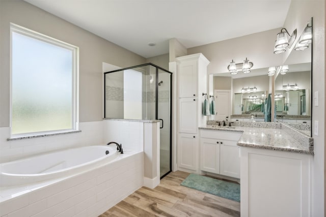 bathroom with vanity, wood-type flooring, and plus walk in shower