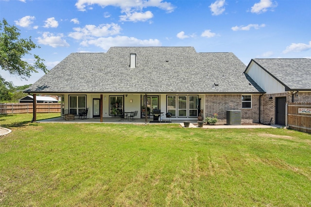 rear view of property featuring a lawn, cooling unit, and a patio area