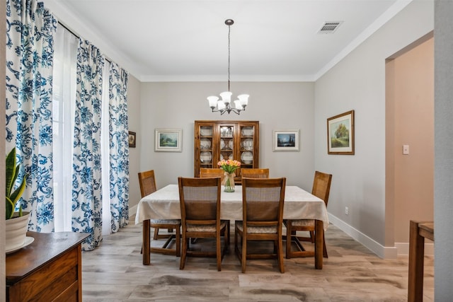 dining room with ornamental molding, light hardwood / wood-style flooring, and a chandelier