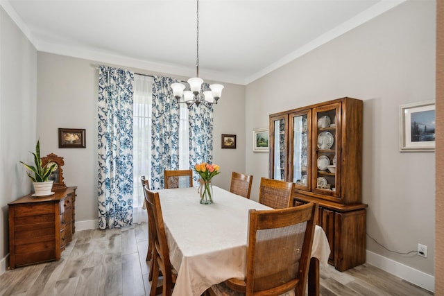 dining space with crown molding, light hardwood / wood-style flooring, and a notable chandelier