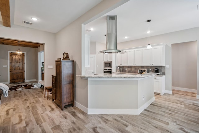 kitchen featuring backsplash, white cabinets, appliances with stainless steel finishes, decorative light fixtures, and island exhaust hood