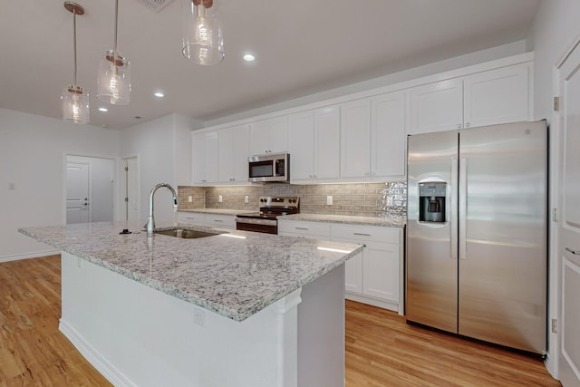 kitchen with white cabinetry, appliances with stainless steel finishes, and a center island with sink