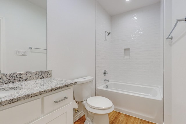 full bathroom with vanity, hardwood / wood-style flooring, tiled shower / bath combo, and toilet