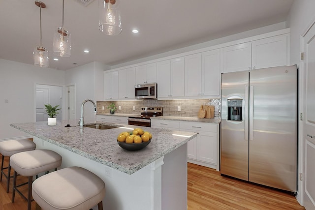 kitchen with sink, stainless steel appliances, an island with sink, and white cabinets