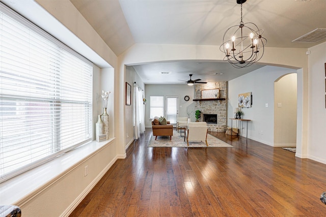 dining room featuring a stone fireplace, ceiling fan with notable chandelier, and dark hardwood / wood-style flooring