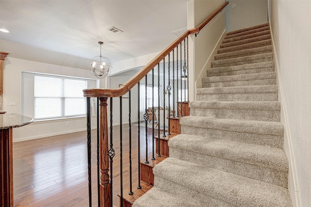 stairway featuring hardwood / wood-style floors and an inviting chandelier