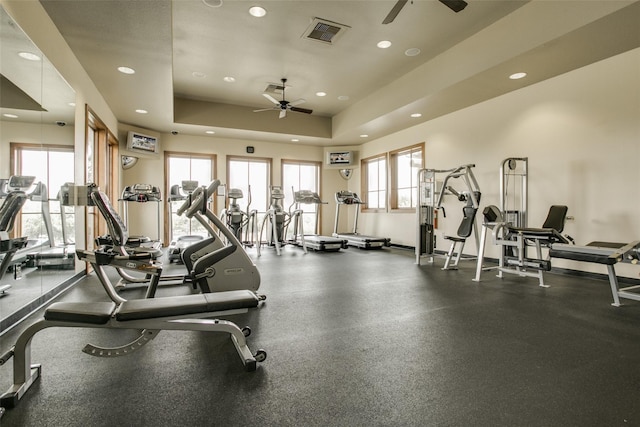 exercise room with a raised ceiling and ceiling fan