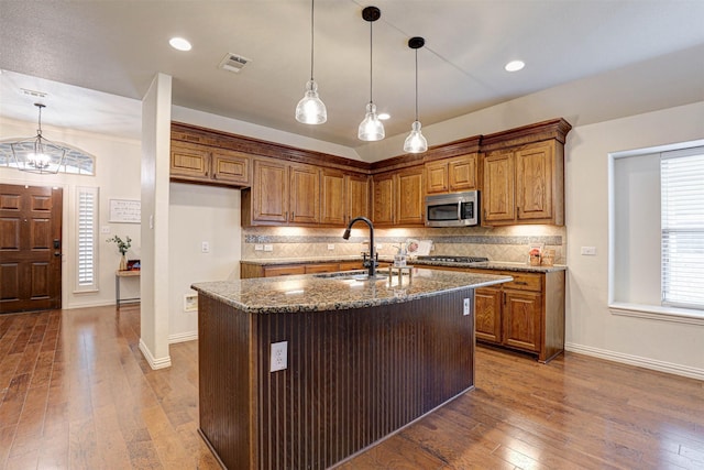 kitchen featuring an island with sink, appliances with stainless steel finishes, stone countertops, and sink