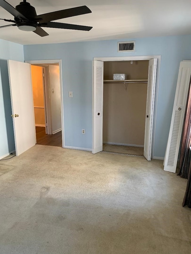 unfurnished bedroom featuring ceiling fan, light colored carpet, and a closet