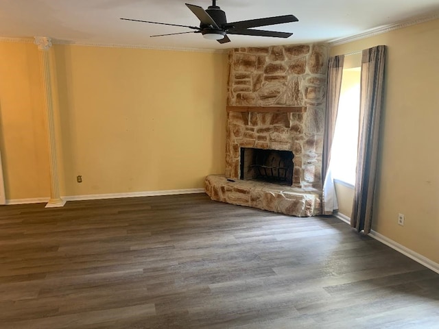 unfurnished living room featuring ceiling fan, a stone fireplace, crown molding, wood finished floors, and baseboards