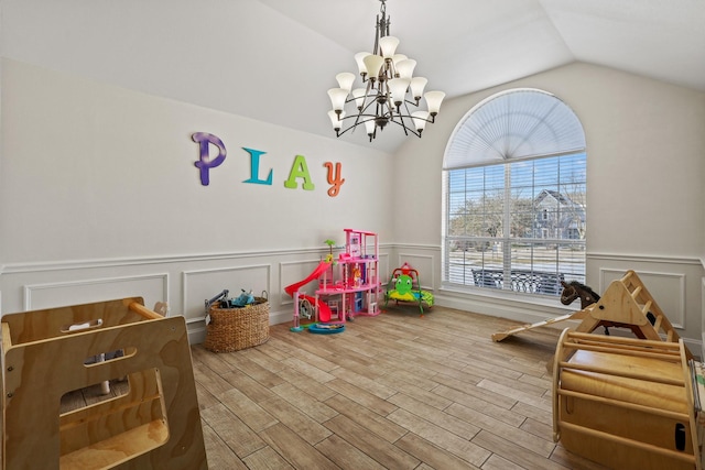 playroom with wood-type flooring, vaulted ceiling, and an inviting chandelier