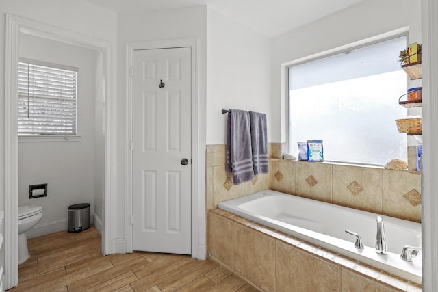 bathroom featuring toilet and tiled tub