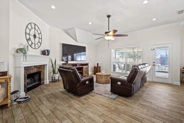 living room with ceiling fan, crown molding, a high end fireplace, and vaulted ceiling