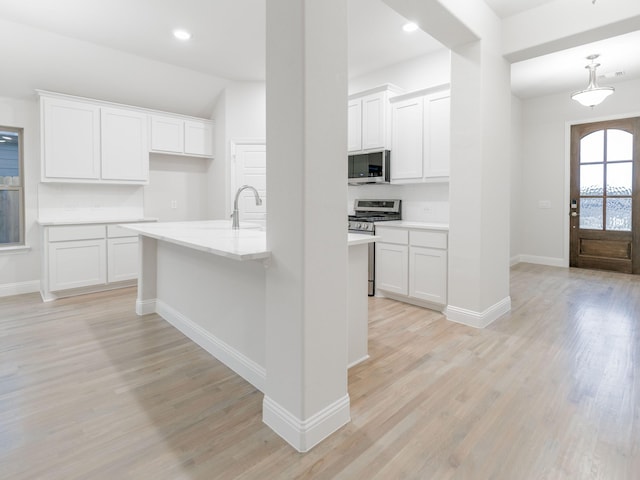 kitchen with stainless steel appliances, light hardwood / wood-style floors, white cabinets, and sink