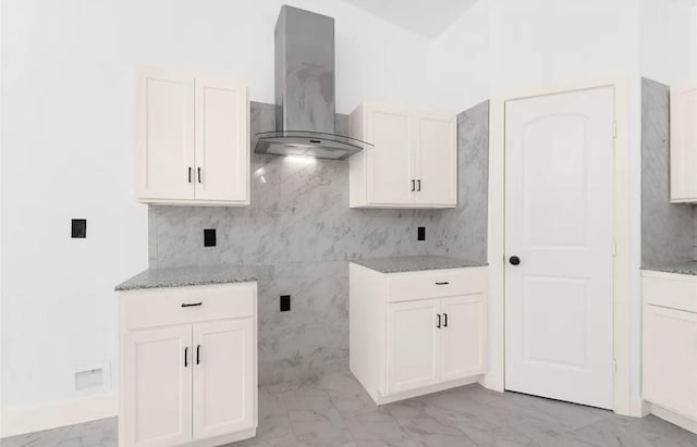 kitchen featuring white cabinets, light stone countertops, and wall chimney range hood