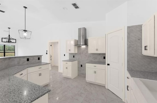 kitchen with white cabinetry, wall chimney range hood, hanging light fixtures, and stone counters