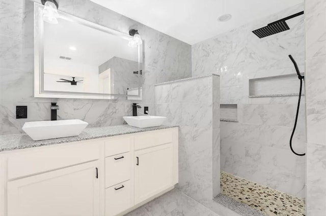 bathroom featuring vanity, a tile shower, and tile walls