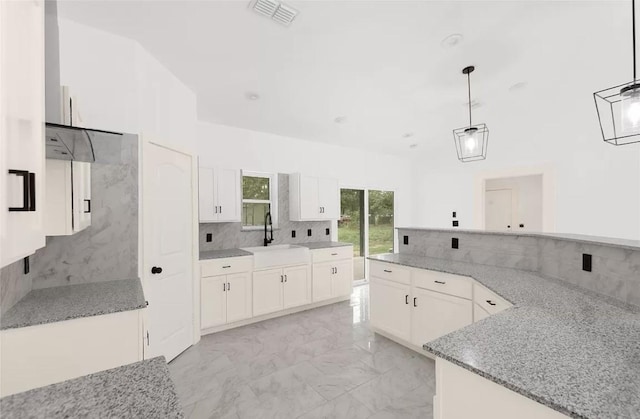 kitchen with white cabinets, pendant lighting, light stone counters, and sink