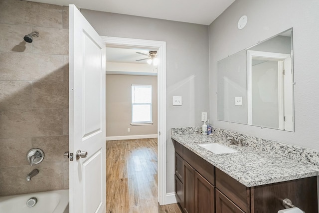 bathroom featuring ceiling fan, vanity, wood-type flooring, and tiled shower / bath