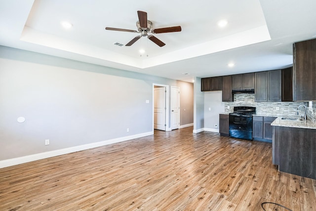 kitchen with a tray ceiling, black electric range, and sink