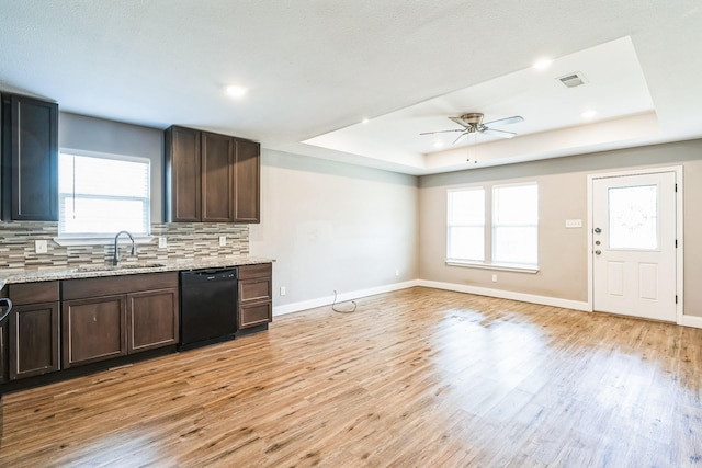 kitchen with backsplash, sink, black dishwasher, and a tray ceiling