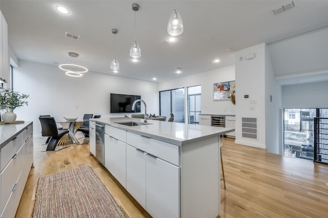 kitchen with dishwasher, sink, pendant lighting, a kitchen island with sink, and white cabinets