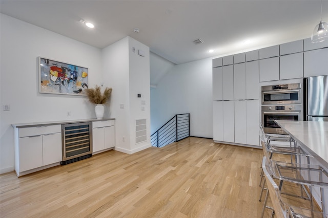 kitchen with gray cabinets, stainless steel appliances, wine cooler, and light hardwood / wood-style floors