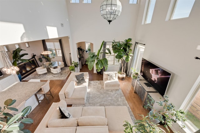 living room with a towering ceiling, light hardwood / wood-style flooring, plenty of natural light, and a notable chandelier