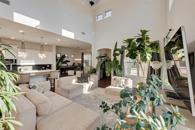 living room with a healthy amount of sunlight, a fireplace, a high ceiling, and a chandelier