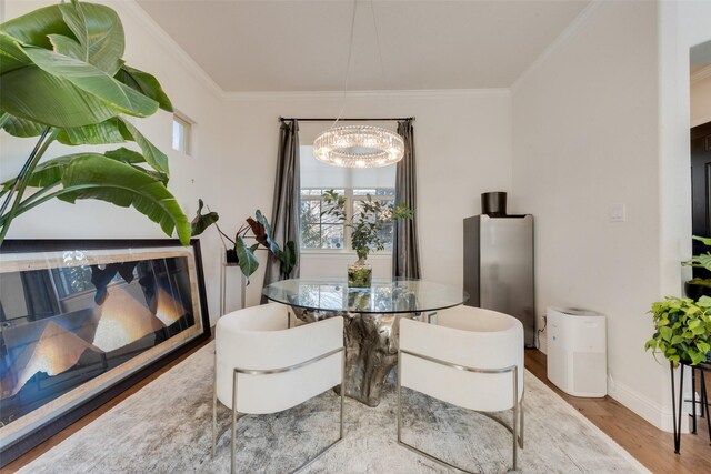 dining space with hardwood / wood-style flooring, a notable chandelier, and crown molding