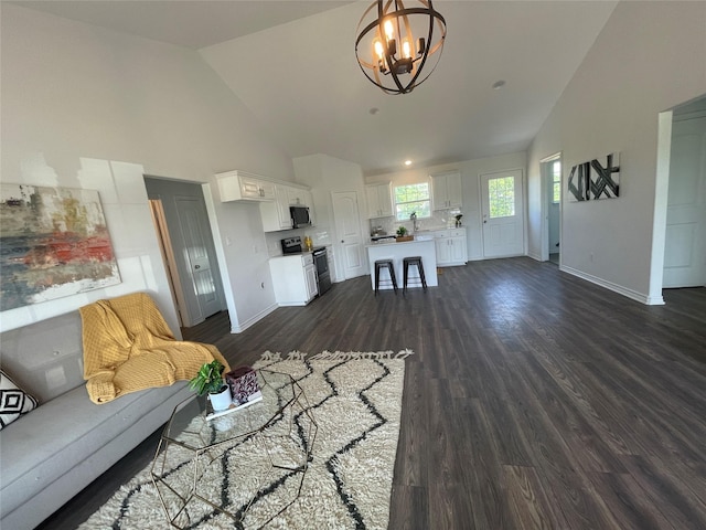 unfurnished living room with dark wood-type flooring, high vaulted ceiling, and a notable chandelier