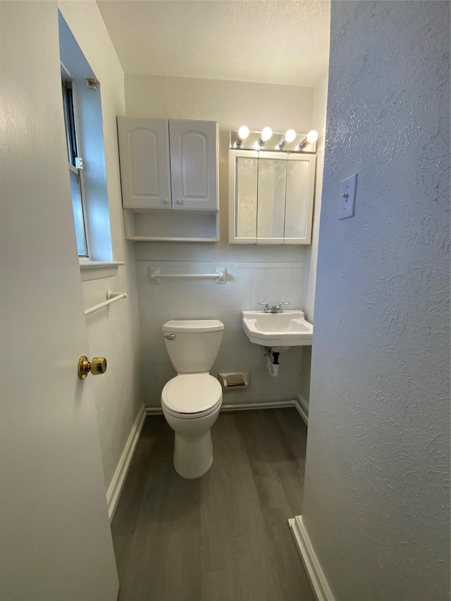 bathroom with toilet, sink, tile walls, and hardwood / wood-style flooring