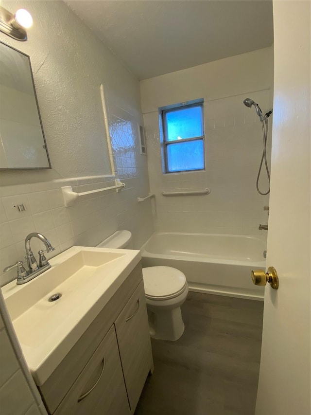 full bathroom featuring tiled shower / bath combo, backsplash, toilet, vanity, and tile walls