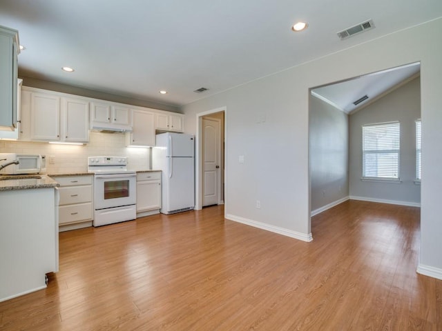 kitchen featuring white appliances, decorative backsplash, light stone countertops, light wood-type flooring, and white cabinetry