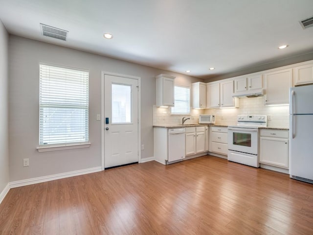 kitchen featuring white appliances, white cabinets, sink, decorative backsplash, and light hardwood / wood-style floors