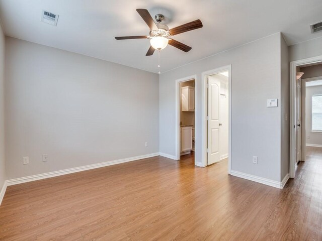 unfurnished bedroom featuring ceiling fan, a walk in closet, and light hardwood / wood-style flooring