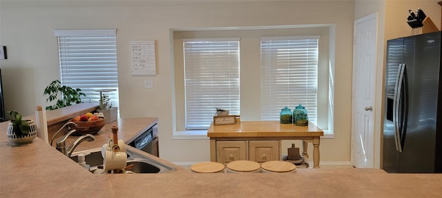 kitchen featuring dishwasher, black fridge, and sink