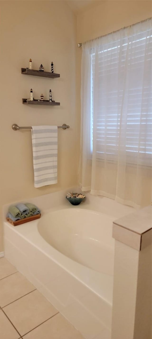 bathroom with a tub to relax in and tile patterned floors