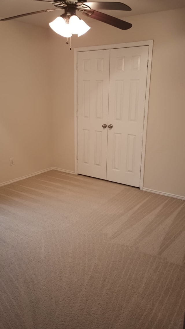 unfurnished bedroom with ceiling fan, carpet flooring, and a closet